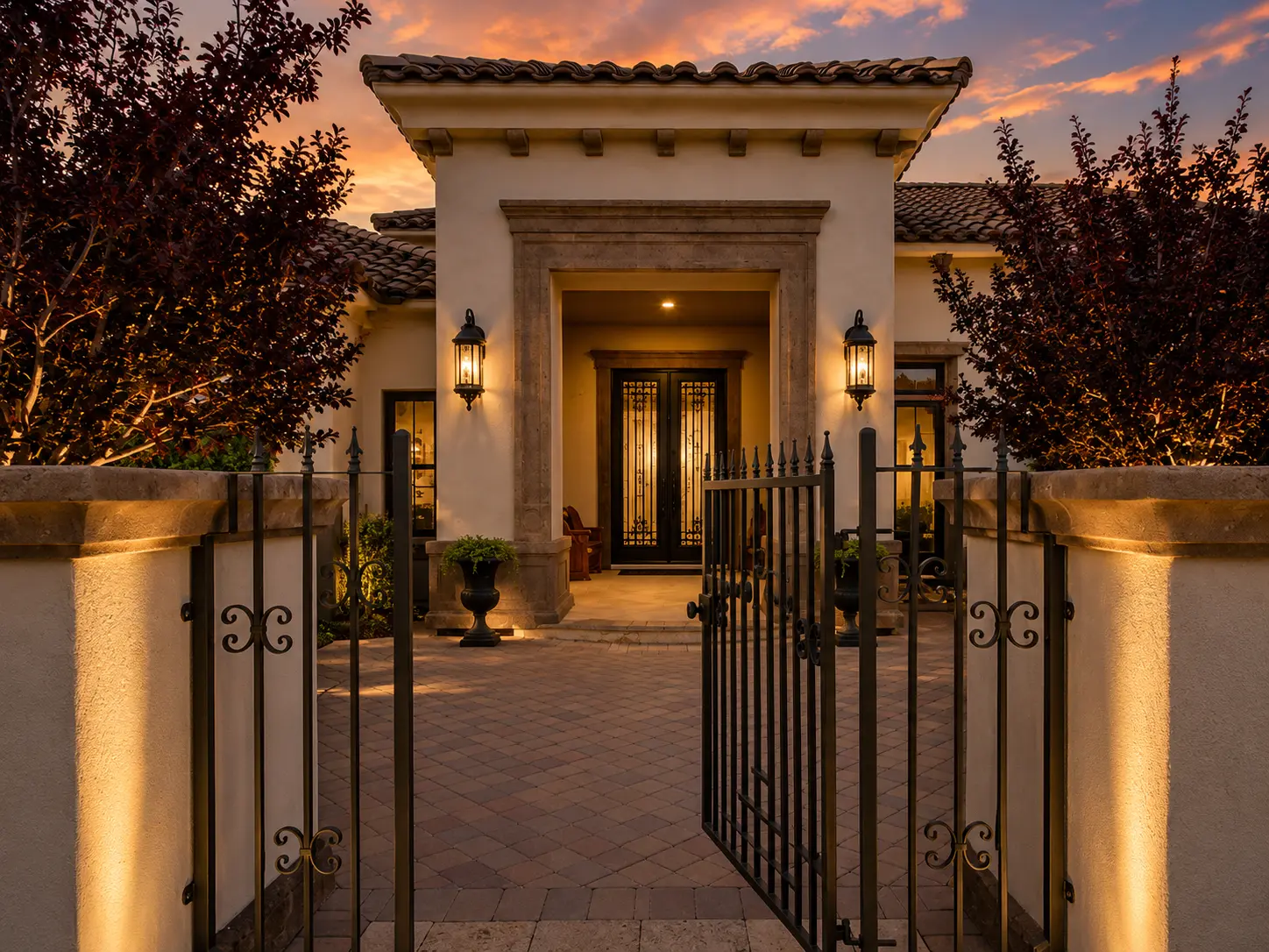 Dartmouth renovation, gated courtyard entry with iron doors and lantern sconces at sunset