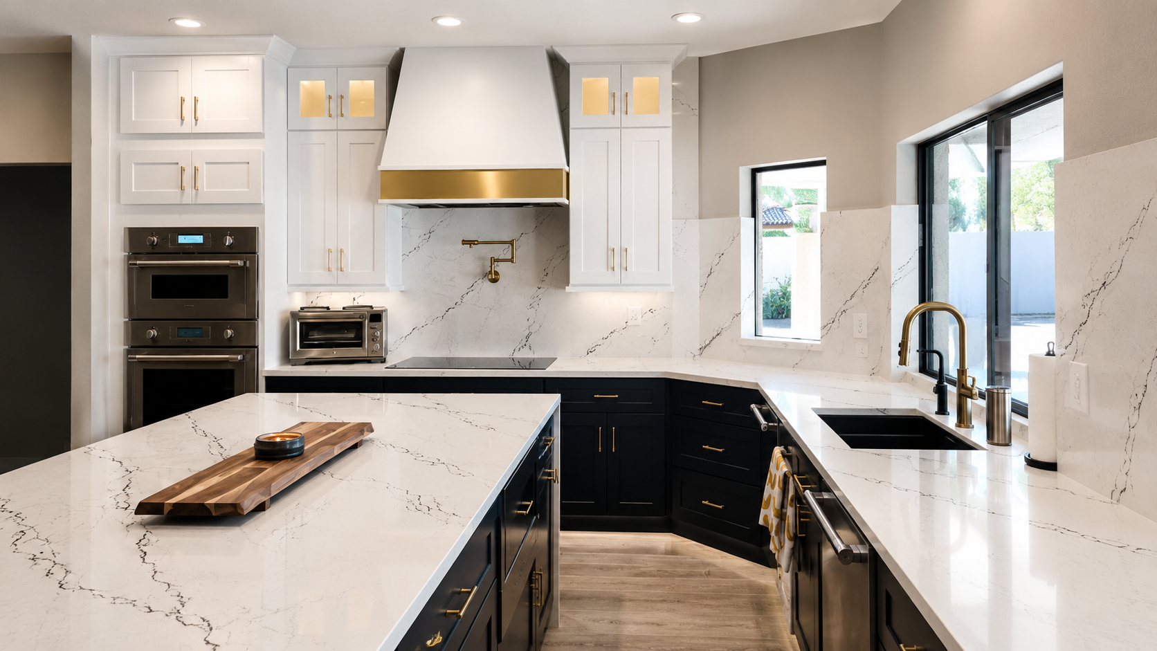 Sutton renovation, after kitchen with white shaker cabinets, brass hardware, navy island, and marble backsplash